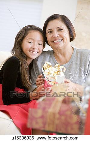 Grandmother And Granddaughter Sitting On Sofa Holding A Christmas Gift View Large Photo Image Stock Photograph - Grandmother And Granddaughter Sitting On Sofa Holding A Christmas Gift. Fotosearch