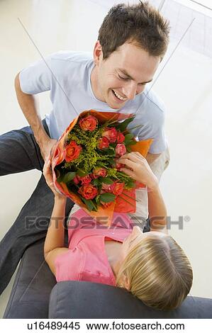 Stock Photography - Husband giving wife flowers and smiling. Fotosearch