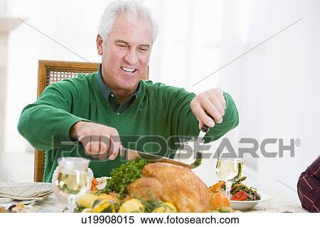 Stock Photography - Man Carving Up Turkey At Christmas Dinner. Fotosearch
