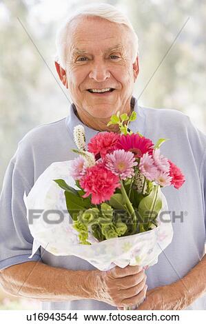 Picture - Man holding flowers and smiling. Fotosearch