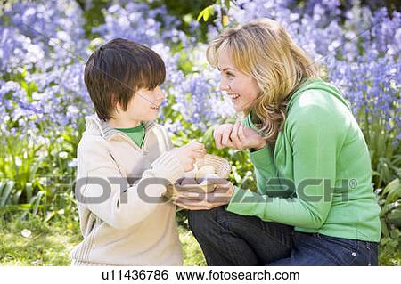 Mother and son on Easter looking for eggs outdoors smiling View Large Photo Image Stock Photograph - Mother and son on Easter looking for eggs outdoors smiling. Fotosearch