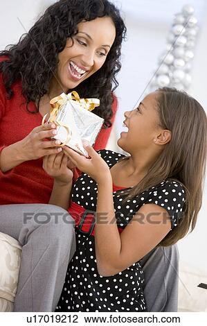 Stock Image - Mother Giving Daughter Her Christmas Present. Fotosearch