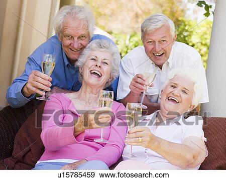 Stock Photo - Two couples on patio drinking champagne and smiling. Fotosearch