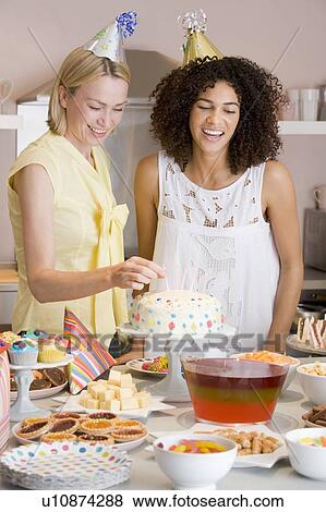 Two women at party putting candles in cake smiling View Large Photo Image Stock Photo - Two women at party putting candles in cake smiling. Fotosearch
