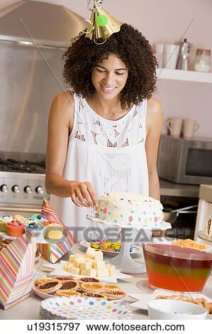 Woman at party fixing cake on table smiling View Large Photo Image Stock Photo - Woman at party fixing cake on table smiling. Fotosearch