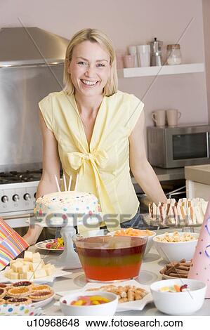 Stock Photo - Woman at party standing by food table smiling. Fotosearch