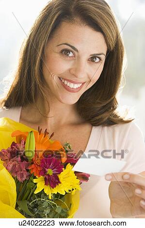 Woman holding flowers and note smiling View Large Photo Image Stock Image - Woman holding flowers and note smiling. Fotosearch