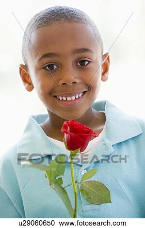 Stock Image - Young boy holding rose smiling. Fotosearch