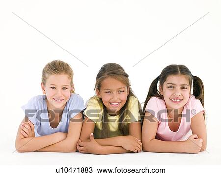 Stock Image - Row of three friends lying down smiling. Fotosearch