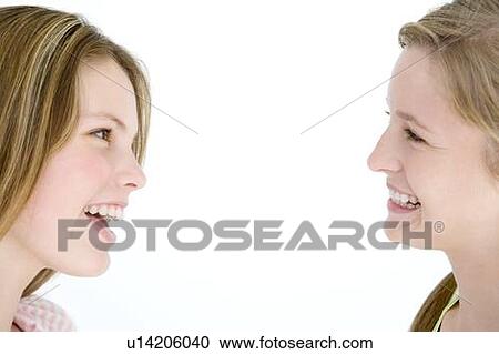 Two girl friends looking at each other smiling View Large Photo Image Stock Image - Two girl friends looking at each other smiling. Fotosearch