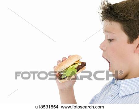 Picture - Young boy eating cheeseburger. Fotosearch