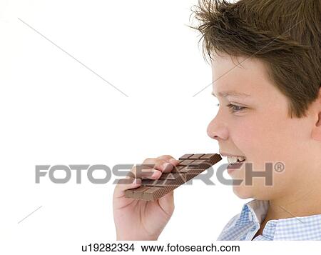 Picture - Young boy eating chocolate bar. Fotosearch