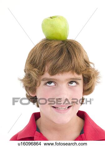 Picture - Young boy with apple on his head smiling. Fotosearch
