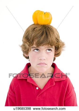 Young boy with yellow pepper on his head frowning View Large Photo Image Stock Photo - Young boy with yellow pepper on his head frowning. Fotosearch