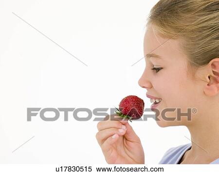 Stock Photography - Young girl eating strawberry smiling. Fotosearch