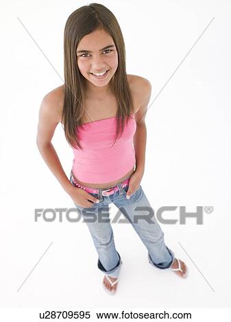Stock Photography - Young girl standing with hands in pockets smiling. Fotosearch