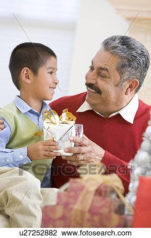 Stock Image - Boy Surprising Father With Christmas Present. Fotosearch
