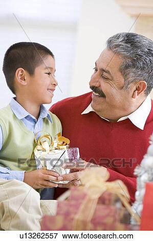 Stock Photo - Boy Surprising Father With Christmas Present. Fotosearch