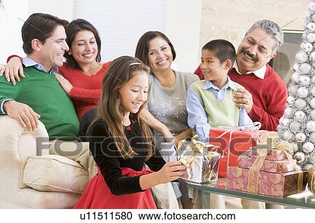 Family Sitting On Sofa In Front Of Christmas Presents, Young Girl Selecting A Gift View Large Photo Image Stock Image - Family Sitting On Sofa In Front Of Christmas Presents, Young Girl Selecting A Gift. Fotosearch