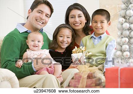 Stock Photo - Family With New Born, Sitting On Sofa, Holding Christmas Gift. Fotosearch