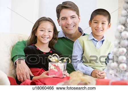 Father And His Son And Daughter Sitting On Sofa, Holding A Christmas Present View Large Photo Image Stock Photograph - Father And His Son And Daughter Sitting On Sofa, Holding A Christmas Present. Fotosearch