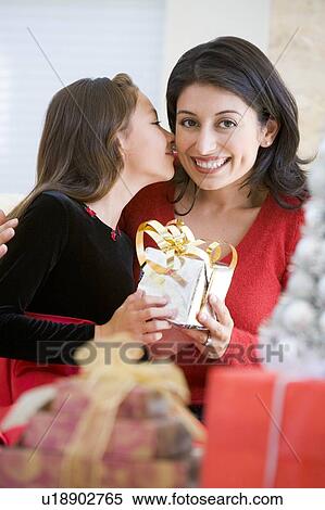 Stock Photography - Girl Surprising Her Mother With Christmas Gift. Fotosearch