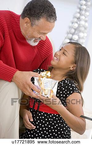 Stock Photography - Grandfather Giving His Granddaughter A Christmas Present. Fotosearch