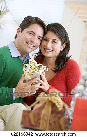 Stock Image - Husband Surprising Wife With Christmas Present. Fotosearch