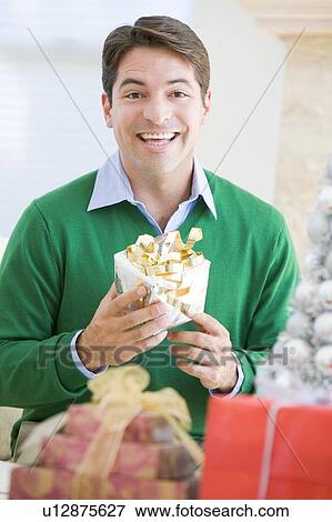Stock Photo - Man Excited To Open Christmas Present. Fotosearch
