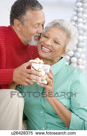 Senior Couple Exchanging A Christmas Gift View Large Photo Image Stock Photography - Senior Couple Exchanging A Christmas Gift. Fotosearch