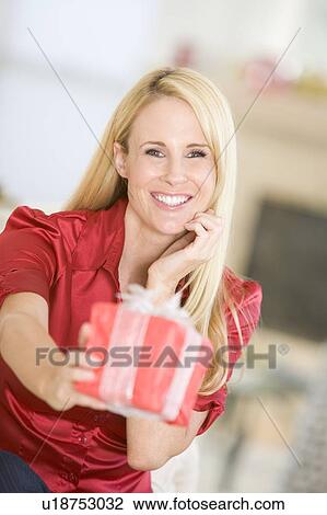 Stock Image - Woman Handing Out Christmas Present. Fotosearch