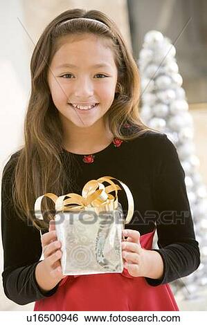 Stock Photograph - Young Girl Smiling, Holding Christmas Gift. Fotosearch
