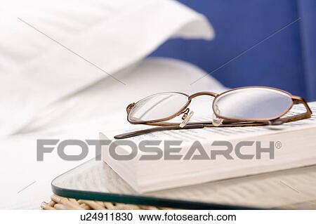 Stock Image - Empty bedroom with focus on eyeglasses and book. Fotosearch
