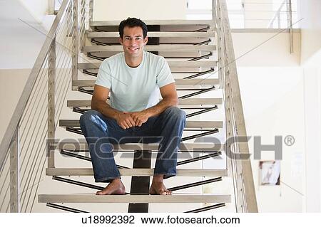 Stock Image - Man sitting on staircase smiling. Fotosearch