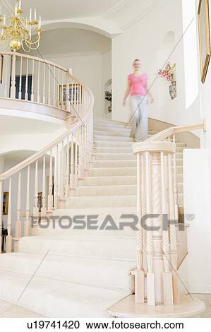 Woman coming down staircase in luxurious home View Large Photo Image Stock Image - Woman coming down staircase in luxurious home. Fotosearch