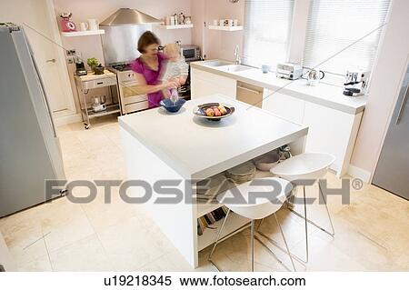 Woman in kitchen whisking on counter holding baby View Large Photo Image Stock Photography - Woman in kitchen whisking on counter holding baby. Fotosearch