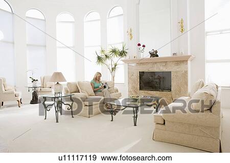 Woman reading magazine in living room View Large Photo Image Stock Photo - Woman reading magazine in living room. Fotosearch