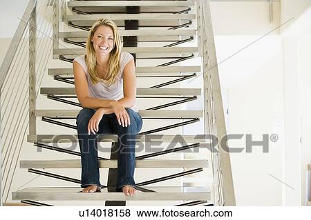 Stock Photo - Woman sitting on stairs smiling. Fotosearch