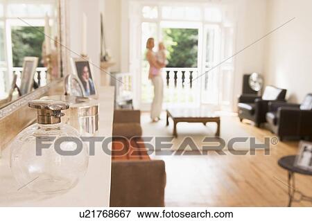 Stock Photo - Woman standing in living room holding baby. Fotosearch