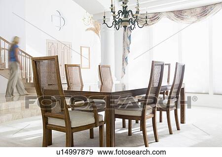 Stock Photo - Woman walking by dining room. Fotosearch