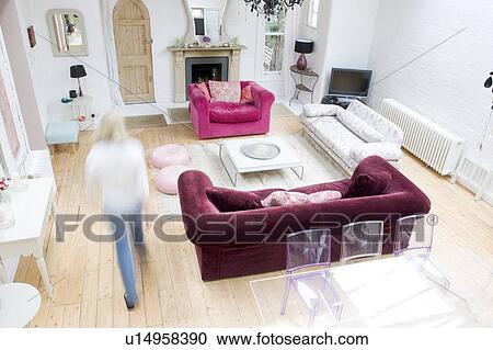 Stock Image - Woman walking through living room. Fotosearch