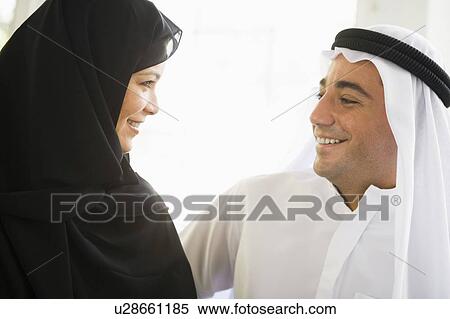 Stock Photography - Couple indoors facing each other smiling (high key). Fotosearch