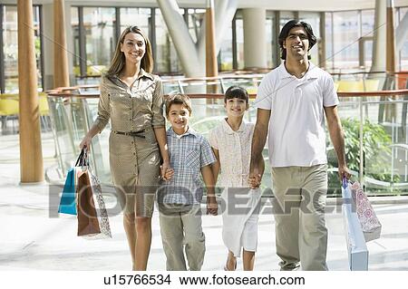 Family walking in mall holding hands and smiling (selective focus) View Large Photo Image Picture - Family walking in mall holding hands and smiling (selective focus). Fotosearch