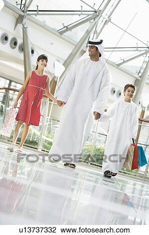 Man and two young children walking in mall holding hands and smiling (selective focus) View Large Photo Image Stock Image - Man and two young children walking in mall holding hands and smiling (selective focus). Fotosearch