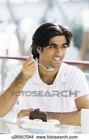 Man at restaurant eating dessert and smiling (selective focus) View Large Photo Image Picture - Man at restaurant eating dessert and smiling (selective focus). Fotosearch