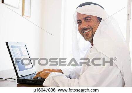 Man in office with laptop smiling (high key/selective focus) View Large Photo Image Stock Photograph - Man in office with laptop smiling (high key/selective focus). Fotosearch
