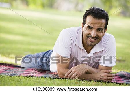 Man lying outdoors at park smiling (selective focus) View Large Photo Image Stock Photo - Man lying outdoors at park smiling (selective focus). Fotosearch