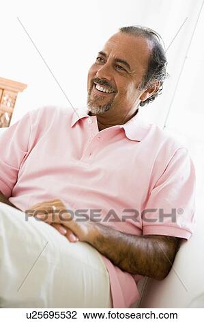 Man sitting in living room smiling (high key) View Large Photo Image Stock Image - Man sitting in living room smiling (high key). Fotosearch