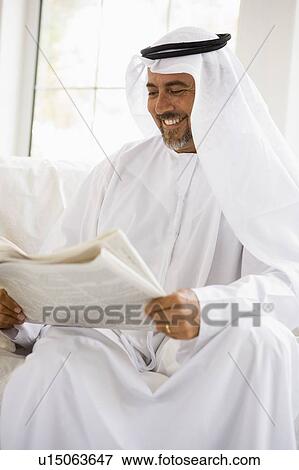 Man sitting indoors with newspaper smiling (high key/selective focus) View Large Photo Image Stock Photo - Man sitting indoors with newspaper smiling (high key/selective focus). Fotosearch