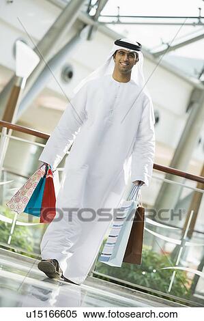 Stock Photography - Man walking in mall smiling (selective focus). Fotosearch